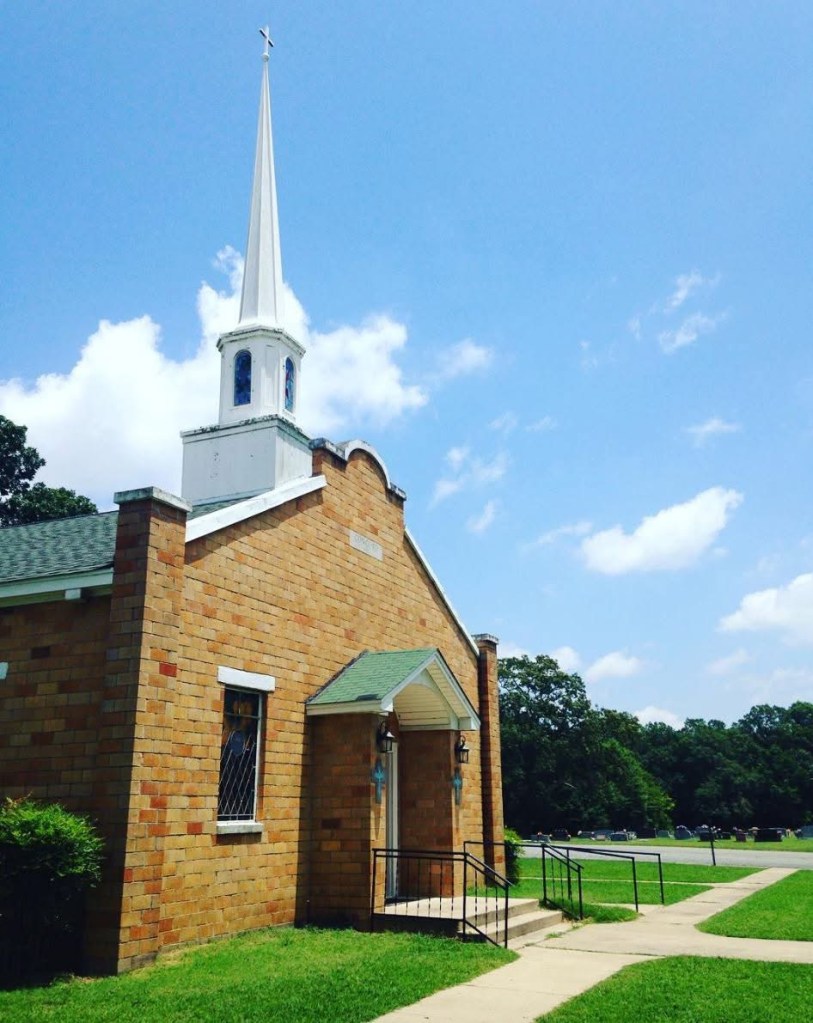 photo of a tan brick church front with blue sky in the background